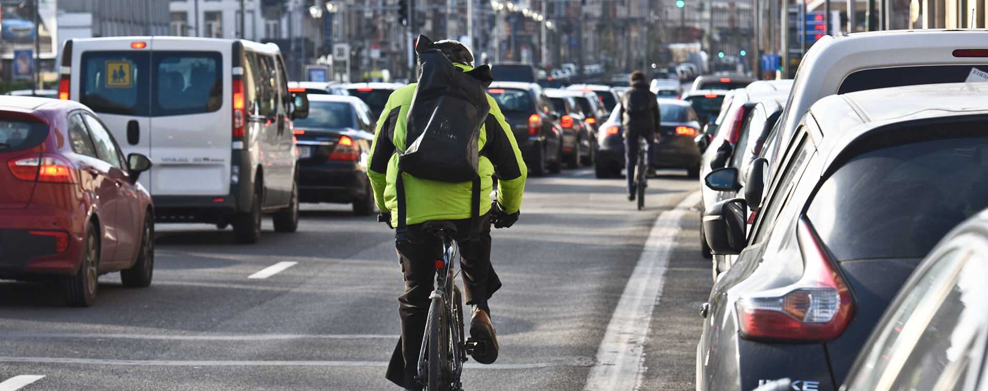 A man cycling through traffic.